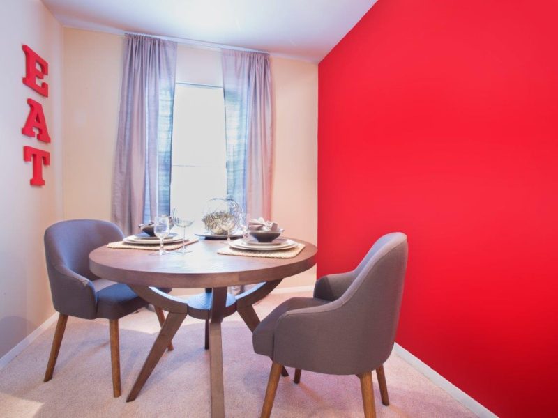 This image shows the premium apartment feature, especially the dining room featuring the elegant dining set and plain red wall color that brings the vibrant vibe.